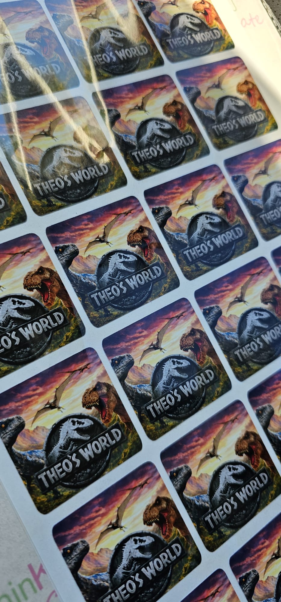 Custom Jurassic-style dinosaur party stickers personalized with 'Theo's World' for birthday favors